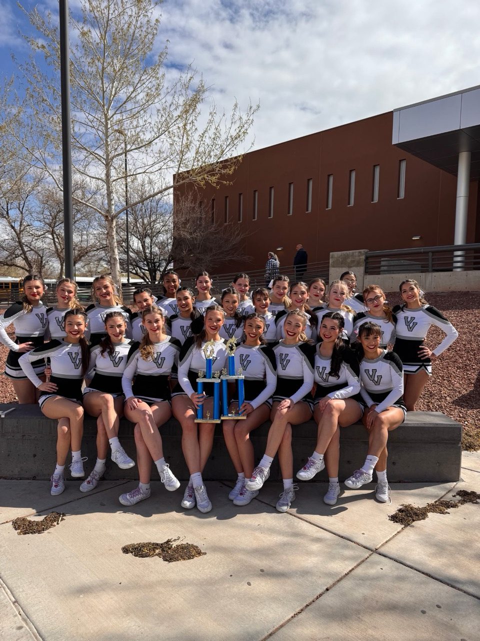 Volcano Vista cheer outside with two trophies
