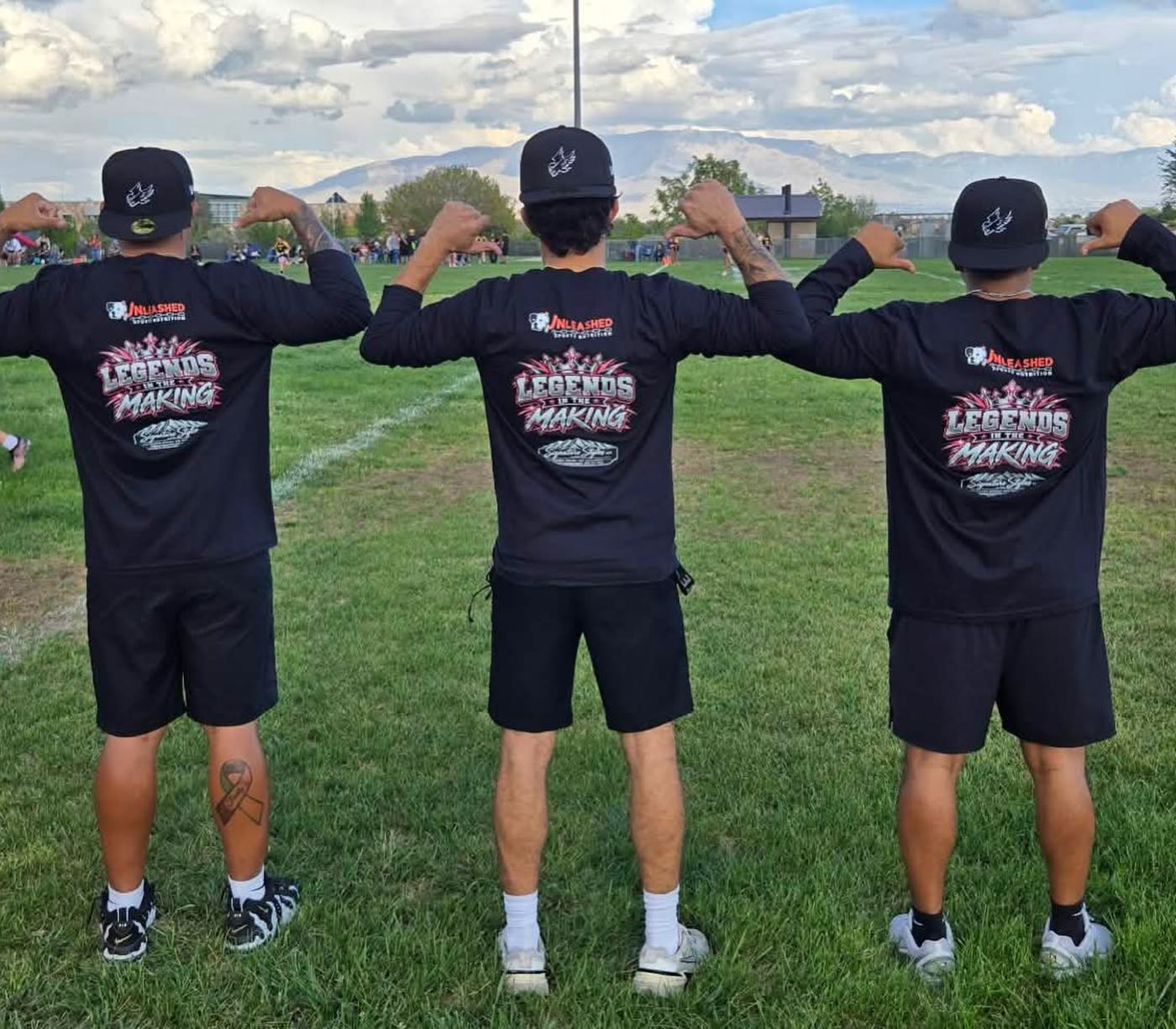 Three coaches with their backs turned, showing the Unleashed Sports Nutrition logo and Legends in the Making print on the team shirts